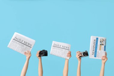 Renkli arka planda gazete ve fotoğraf makinesi olan kadın eller