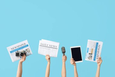 Gazeteli, mikrofonlu ve renkli arka planlı modern aletli kadın eller.