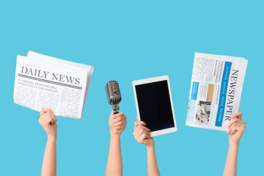 Renkli arka planda gazete, mikrofon ve tablet bilgisayarlı kadın eller