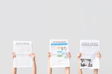 Gri arka planda gazeteleri olan kadın eller.