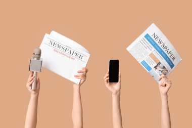 Renkli arka planda gazete, cep telefonu ve mikrofon olan kadın elleri