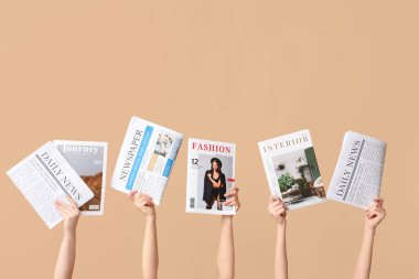 Dergileri ve gazeteleri renkli arka planda olan kadın elleri
