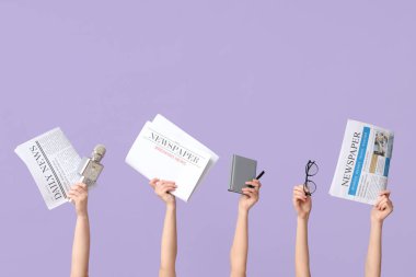 Gazete, mikrofon ve eflatun arkaplanda not defteri olan kadın eller.