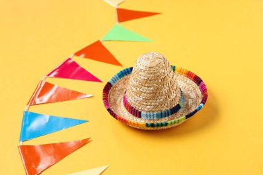 Mini sombrero ve Festa Junina kutlamaları için sarı arka planda renkli bayraklar