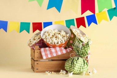 Festa Junina kutlamaları için arkaplanda lezzetli patlamış mısır, paket poşet ve bayraklar bulunan tahta sepet.