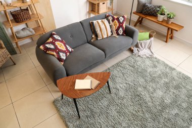 Oturma odasının içinde siyah kanepe, sehpa ve minderler var.