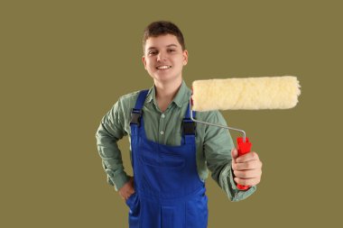 Yeşil arka planda boya silindiri olan genç dekoratör