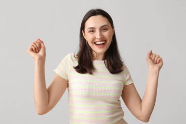 Gri arka planda gülümseyen genç kadın