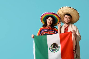 Mavi arka planda Meksika bayrağı olan şapkalı genç ve güzel bir çift. Cinco de Mayo kutlaması