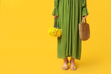 Hasır çantalı güzel bir kadın ve sarı arka planda güzel narsisli çiçekler, yakın plan.