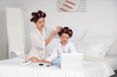 Küçük kızı kıvırcık saçlı, genç Asyalı kadın.