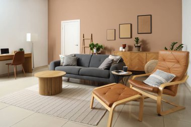 Bej renkli bir oturma odası, rahat bir kanepe, sehpa ve koltuk.