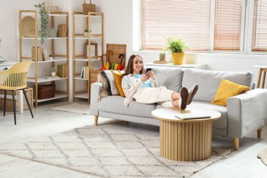 Oturma odasında cep telefonuyla konuşan genç ve güzel bir kadın.