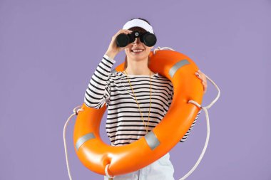 Kurtarma yüzüklü genç bayan cankurtaran leylak arka planda dürbünle bakıyor.