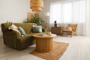 Beyaz oturma odasının içinde yeşil kanepe, lamba ve kahve masası var.