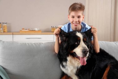 Oturma odasında sevimli tüylü köpeği olan bir çocuk.