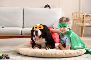 Süper kahraman kostümlü çocuk ve köpek evcil hayvan yatağında kanepede yatıyor.