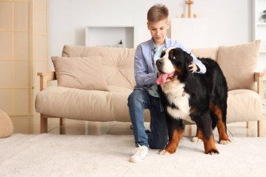 Çocuk ve sevimli tüylü köpek oturma odasındaki kanepenin yanında.