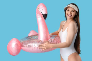 Mavi arka planda şişirilebilir yüzüğü olan gülümseyen genç kadın.