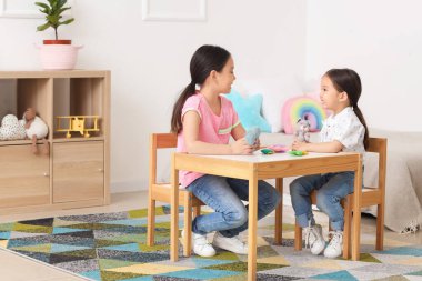 Küçük şirin Asyalı mutlu kız kardeşler çocuk odasında sevimli oyuncaklarla oynuyorlar.