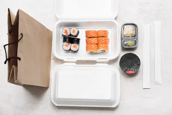 Plastikbehälter Mit Leckeren Sushi Rollen Essstäbchen Und Papiertüten Auf Weißem lizenzfreie Stockfotos
