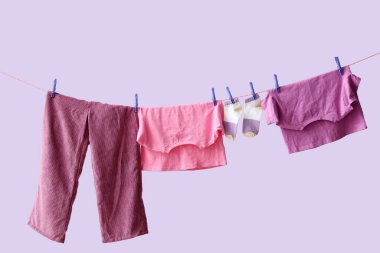 Temiz giysiler ipte leylak arka planda asılı.