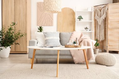 Koltuğu, çiçekleri, raf ünitesi ve sehpası olan şık bir oturma odası.