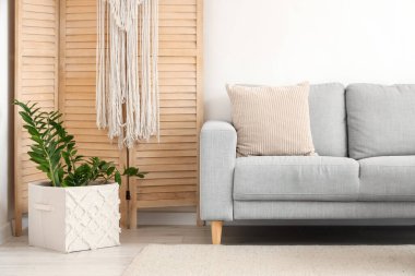 Oturma odasının içinde rahat bir kanepe ve çiçek var.