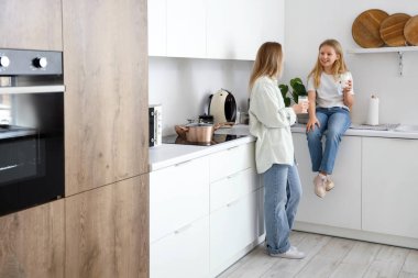 Mutlu kız ve annesi evde oturmuş süt içiyorlar.