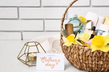 Dekoratif kozmetik ürünleri, çiçekler ve yanan mumlarla dolu bir hediye sepeti ışık masasında Anneler Günü kutlaması için.