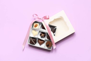 Lezzetli çikolata şekerleriyle dolu bir kutu ve leylak arkaplan