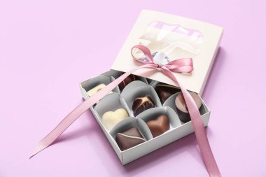 Lezzetli çikolata şekerleriyle dolu bir kutu ve leylak arkaplan