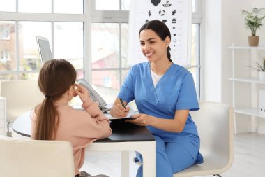 Klinikte küçük bir kızla çalışan kadın göz doktoru.