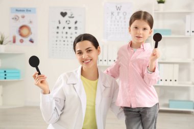 Female ophthalmologist and little girl with occluders in clinic clipart