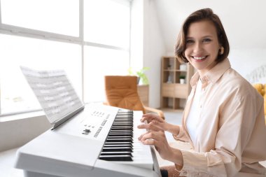 Evde sentezleyici çalan genç bir kadın.