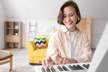 Evde sentezleyici çalan genç bir kadın.