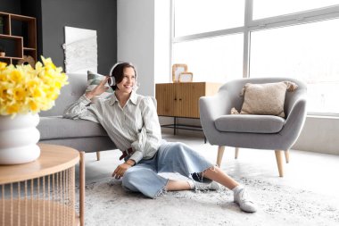 Kulaklıklı güzel bir kadın evde yerde müzik dinliyor.