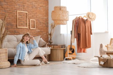 Genç ve güzel bir kadın güzel bir oturma odasında yerde oturuyor.