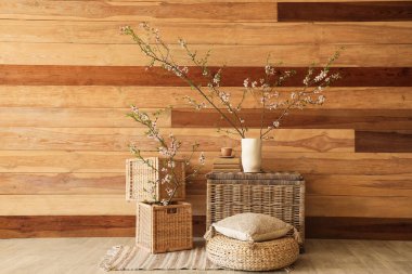 Oturma odasındaki ahşap duvarın yanında çiçek açan vazo ve kutular.