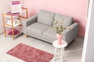 Çiçek açan güzel dalları olan bir vazo ve evdeki kanepe.