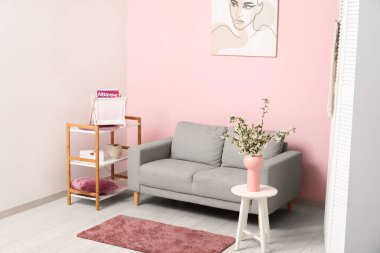 Çiçek açan güzel dalları olan bir vazo ve evdeki kanepe.