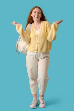 Mavi arka planda sırt çantası olan mutlu kız öğrenci.