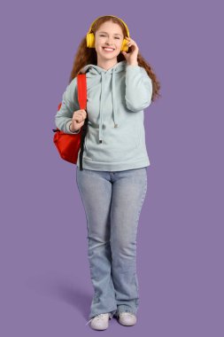 Sırt çantalı ve kulaklıklı mutlu bayan öğrenci.