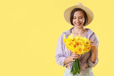 Sarı arka planda nergis olan şapkalı genç bir kadın.