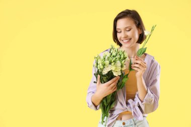 Sarı arka planda Eustoma çiçekleri olan genç bir kadın.