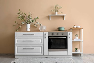 Bej mutfaktaki beyaz tezgahın üzerinde çiçek açan bir vazo.