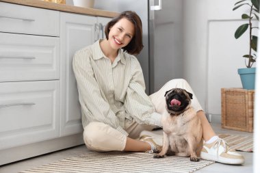 Mutfakta yerde oturan sevimli köpekli genç bir kadın.