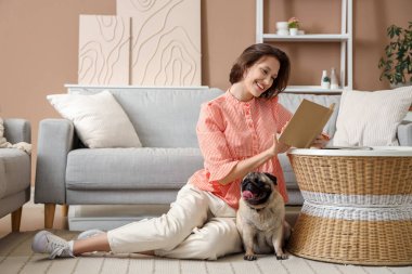 Evde sevimli köpekli genç bir kadın kitap okuyor.