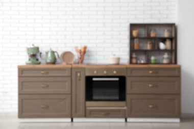 Fırın, kahverengi tezgah ve raf ünitesiyle mutfağın şık iç mekanı bulanık görünüyor.