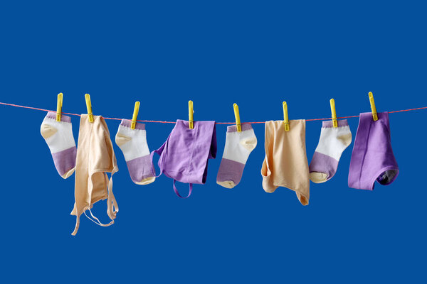 Clean clothes hanging on rope against blue background